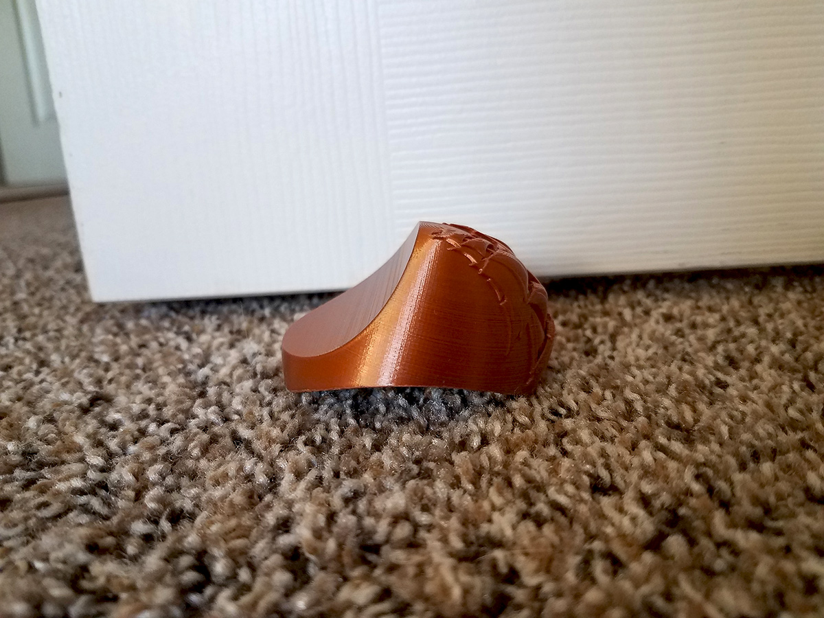 Side profile of the physical carpet door stopper demonstrating how the wedge shape interacts with carpet and door pressure.
