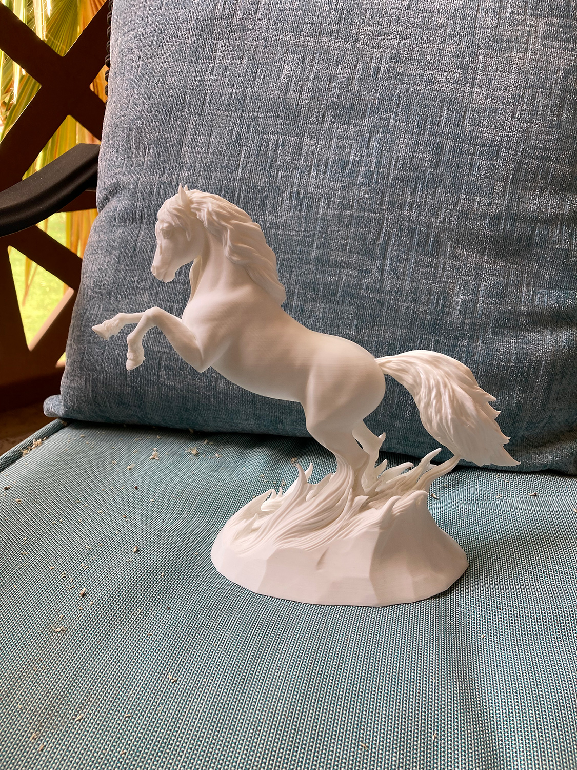 White 3D printed rearing horse sculpture on a chair, highlighting clean form, movement, and matte surface detail