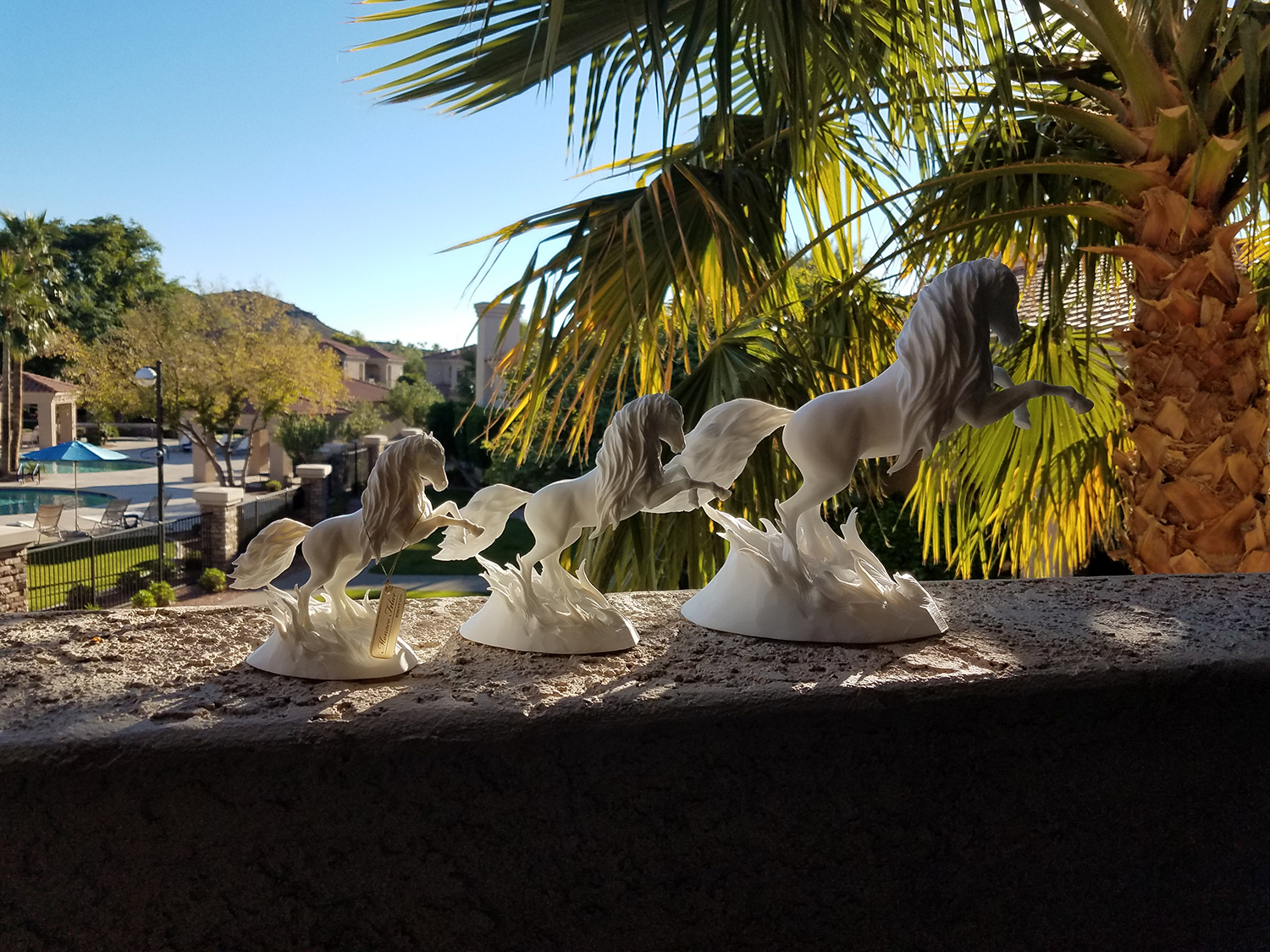 Multiple 3D printed horse sculptures in different sizes displayed outdoors, demonstrating scalability and variation of the same artwork