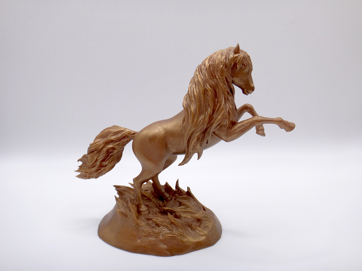 Small rearing horse sculpture with bronze-toned surface and flowing form