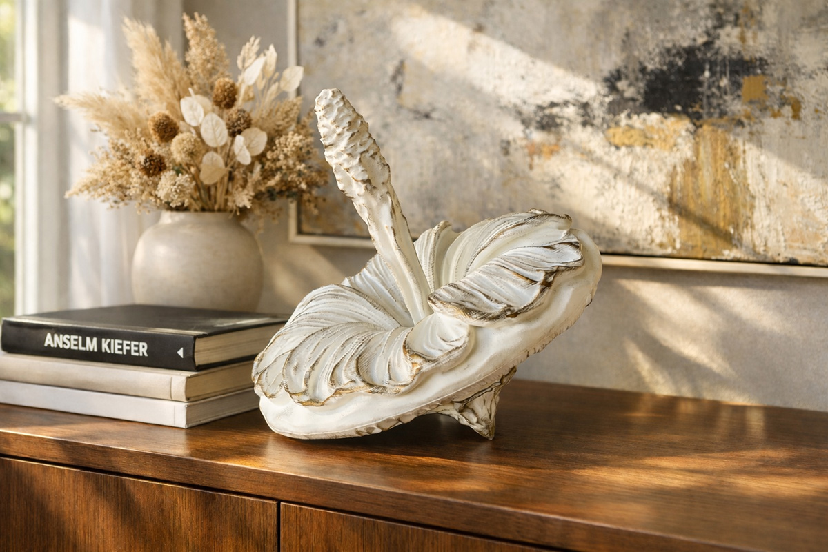 Decorative mallow sculpture in white and gold placed on a wooden cabinet — modern interior with soft natural light