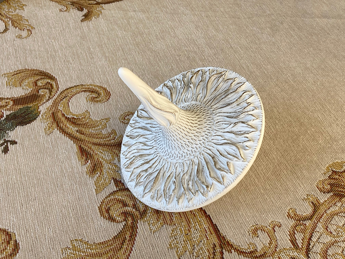 Sunflower sculptural spinning top in white finish — physical object highlighting relief detail and tactile surface