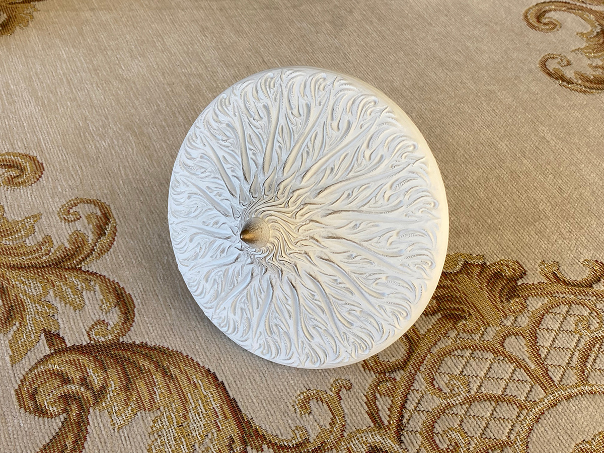 Sculptural spinning top underside — flowing organic pattern inspired by thistle in white physical sculpture