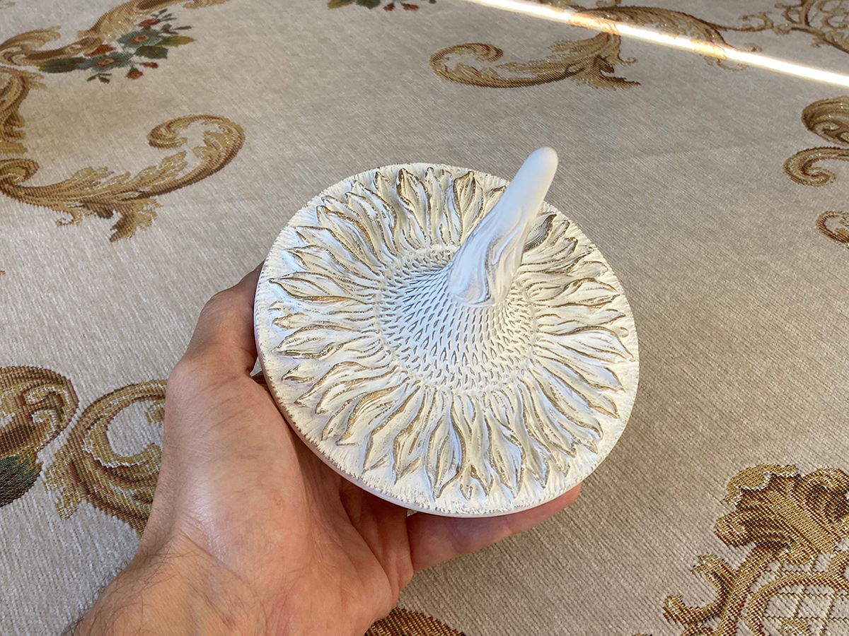 Sunflower sculptural top held in hand — scale, tactile quality and detailed surface of the object