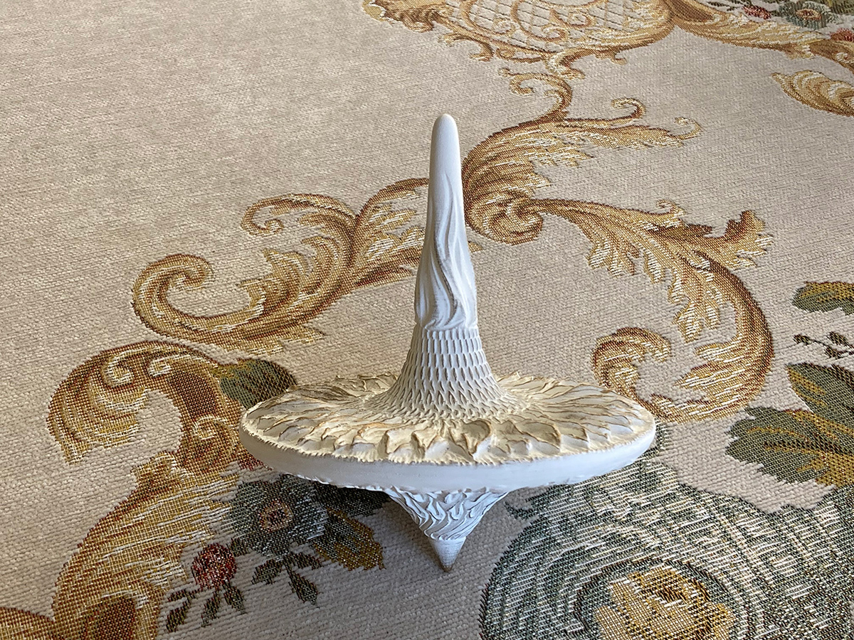 Sculptural spinning top standing upright — balanced form and vertical silhouette of sunflower-inspired object