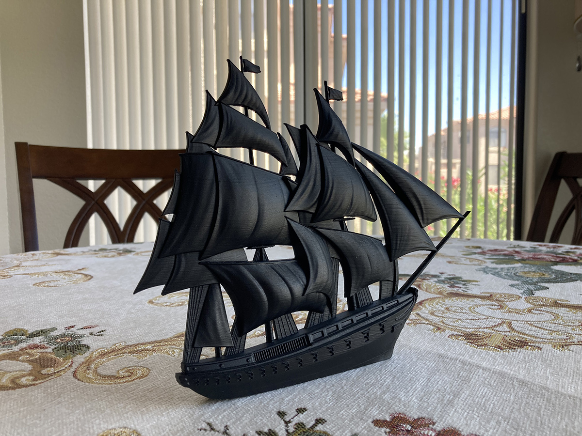 Black sailing ship sculpture placed on table, showing clean silhouette and sculptural form in interior lighting